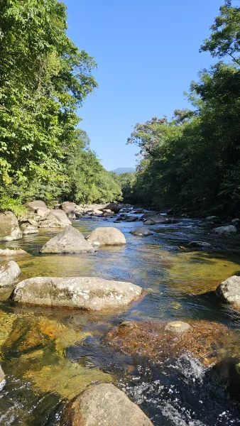 Trecho do rio entre pedras grandes, com floresta nas duas margens