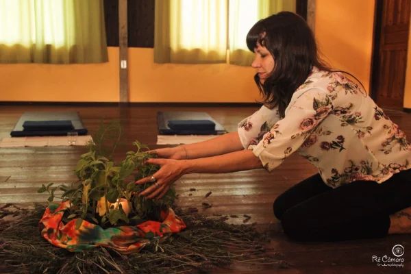 Mulher montando uma mandala de flores e folhas no chão do salão