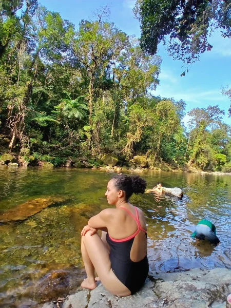 Pessoa nadando no rio, cercada de floresta